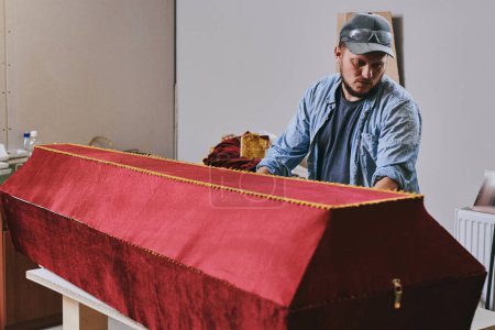 Foto de Trabajos de carpintería hace ataúd de terciopelo rojo en taller de carpintería. Hombre haciendo muebles professionall - Imagen libre de derechos