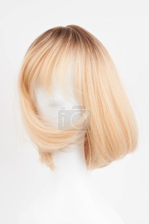 Photo for Natural looking blonde fair wig on white mannequin head. Short hair cut on the plastic wig holder isolated on white background, front vie - Royalty Free Image