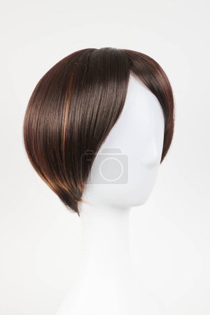 Photo for Natural looking dark brunet wig on white mannequin head. Short brown hair on the plastic wig holder isolated on white backgroun - Royalty Free Image