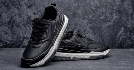 Téléchargez les photos : Baskets homme en cuir noir isolé sur fond grunge noir, chaussures de sport - en image libre de droit