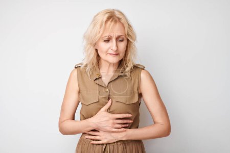 Photo for Portrait of mature woman suffering from stomach pain isolated on white studio background. Intestinal and stomach problems concep - Royalty Free Image