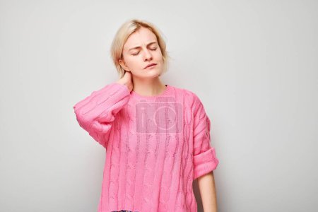 Foto de Retrato de una joven que sufre de dolor, tocando el cuello aislado sobre fondo blanco del estudio. Psicosomática del estrés, enfermedad degenerativa de la columna vertebral - Imagen libre de derechos
