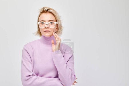 Photo for Portrait Caucasian young blond woman smiling joyfully isolated on white studio background. Happy girl in lilac sweater and glasses with glad face expression - Royalty Free Image