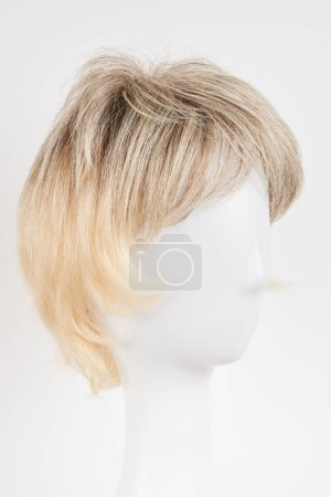 Téléchargez les photos : Perruque blonde blonde naturelle sur tête de mannequin blanche. Cheveux courts coupés sur le porte-perruque en plastique isolé sur fond blanc - en image libre de droit