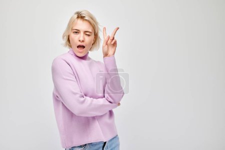 Photo for Portrait of positive girl showing peace and love gesture with fingers isolated on white studio background. Selfie pose, hello my friend concep - Royalty Free Image