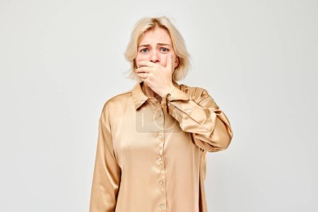 Foto de Retrato de una chica cubriéndose la boca con la mano aislada sobre fondo blanco del estudio. Mala respiración, olor a sudor - Imagen libre de derechos