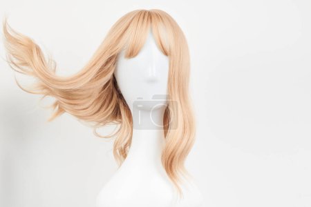 Téléchargez les photos : Perruque blonde blonde naturelle sur tête de mannequin blanche. Cheveux mi-longs coupés sur le porte-perruque en plastique isolé sur fond blanc, front vie - en image libre de droit