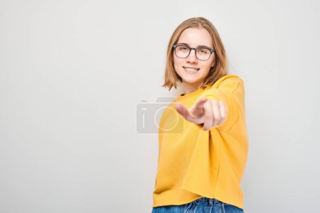 Photo for Portrait of confident student girl chooses you points finger at camera isolated on white studio background. Welcome gesture, join our team concept - Royalty Free Image