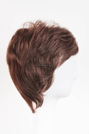 Téléchargez les photos : Perruque brune foncée à l'aspect naturel sur tête de mannequin blanche. Cheveux bruns courts sur le porte-perruque en plastique isolé sur fond blanc, vie latérale - en image libre de droit