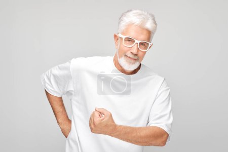 Téléchargez les photos : Portrait d'un homme confiant de 50 ans montrant des biceps, démontrant une force isolée sur fond de studio blanc. Concept de gagnant chanceux - en image libre de droit