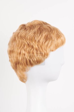 Photo for Natural looking blonde fair wig on white mannequin head. Short hair cut on the plastic wig holder isolated on white background, side vie - Royalty Free Image