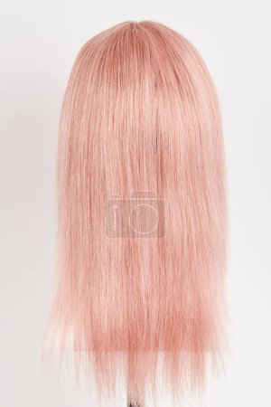 Téléchargez les photos : Perruque blonde rose à l'aspect naturel sur tête de mannequin blanche. Cheveux longs coupés sur le support de perruque en plastique isolé sur fond blanc - en image libre de droit