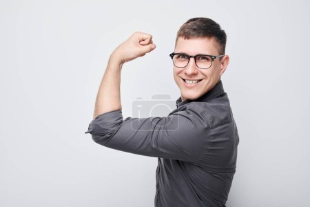 Photo for Portrait of confident young man showing biceps, demonstrating strength isolated on white studio background. Lucky winner concept - Royalty Free Image