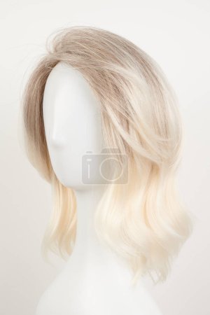 Téléchargez les photos : Perruque blonde blonde naturelle sur tête de mannequin blanche. Cheveux mi-longs coupés sur le porte-perruque en plastique isolé sur fond blanc - en image libre de droit