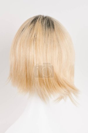 Téléchargez les photos : Perruque blonde blonde naturelle sur tête de mannequin blanche. Cheveux courts coupés sur le porte-perruque en plastique isolé sur fond blanc, dos en vie - en image libre de droit