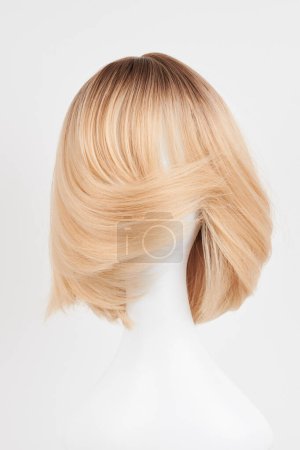 Photo for Natural looking blonde fair wig on white mannequin head. Short hair cut on the plastic wig holder isolated on white backgroun - Royalty Free Image