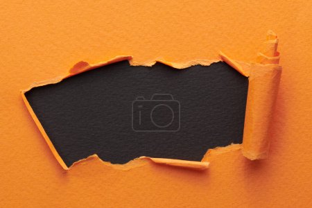 Photo for Frame of ripped paper with torn edges. Window for text with copy space orange black colors, shreds of notebook pages. Abstract backgroun - Royalty Free Image