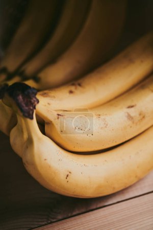 Foto de Primer plano de un ramo de plátanos sobre un fondo de mesa de cocina de madera - Imagen libre de derechos