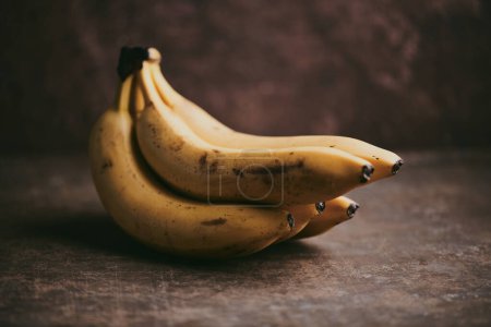 Foto de Primer plano de un ramo de plátanos sobre un fondo de textura marrón - Imagen libre de derechos