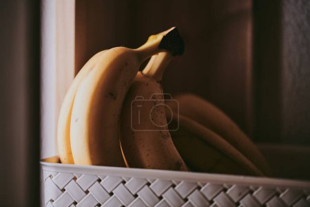 Téléchargez les photos : Gros plan d'un bouquet de bananes dans un panier sur un fond de table - en image libre de droit