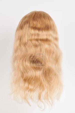 Téléchargez les photos : Perruque blonde naturelle sur tête de mannequin blanche. Cheveux longs sur le support de perruque en plastique isolé sur fond blanc, arrière vie - en image libre de droit