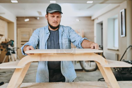 Foto de Carpintero trabaja con madera en taller de carpintería. Hombre haciendo carpintería profesionalmente - Imagen libre de derechos