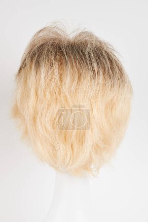 Photo for Natural looking blonde fair wig on white mannequin head. Short hair cut on the plastic wig holder isolated on white background, back vie - Royalty Free Image
