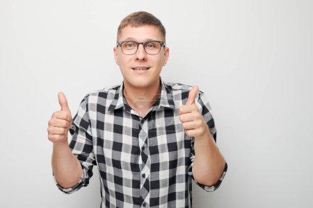 Photo for Portrait of young Caucasian man smiling joyfully showing thumbs up gesture isolated on white studio background. Approves good choice, right decisio - Royalty Free Image
