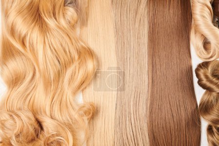Foto de Cabello brillante de aspecto natural, racimo de diferentes colores rizos y pelucas aisladas sobre fondo blanco - Imagen libre de derechos