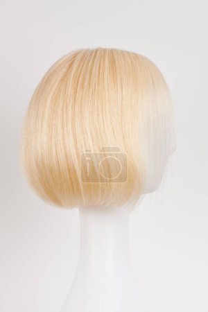 Téléchargez les photos : Perruque blonde blonde naturelle sur tête de mannequin blanche. Coupe de cheveux courts sur le support de perruque en plastique isolé sur fond blanc, vie latérale - en image libre de droit
