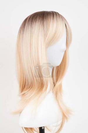Photo for Natural looking blonde wig on white mannequin head. Long hair on the plastic wig holder isolated on white backgroun - Royalty Free Image