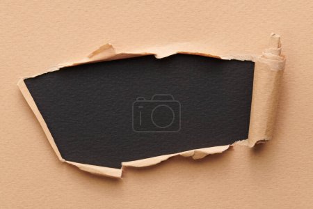 Photo for Frame of ripped paper with torn edges. Window for text with copy space black beige colors, shreds of notebook pages. Abstract backgroun - Royalty Free Image