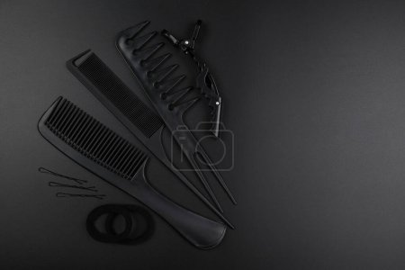Foto de Herramientas de peluquería primer plano aislado sobre fondo negro. Conjuntos de peines, clips, horquillas, concepto de salón de belleza del cabello - Imagen libre de derechos
