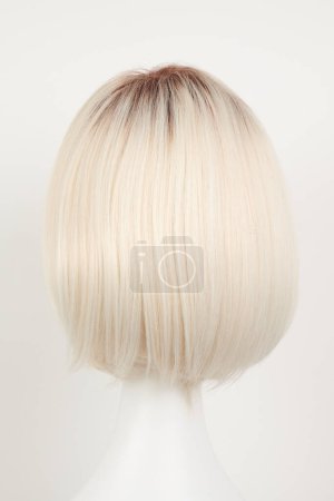 Téléchargez les photos : Perruque blonde blonde naturelle sur tête de mannequin blanche. Cheveux courts coupés sur le porte-perruque en plastique isolé sur fond blanc, dos en vie - en image libre de droit