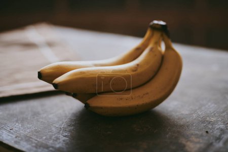 Téléchargez les photos : Gros plan d'un bouquet de bananes sur un fond brun texturé - en image libre de droit