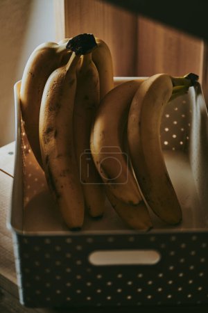 Photo for Close-up of a bunch of bananas in a basket on a table background - Royalty Free Image