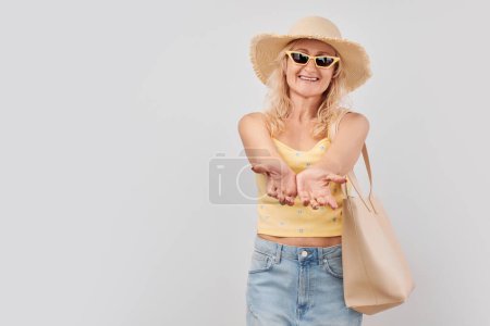 Photo for Beautiful mature woman 50 years old holding something in hand, demonstrating empty space for product or text isolated on white studio backgroun - Royalty Free Image