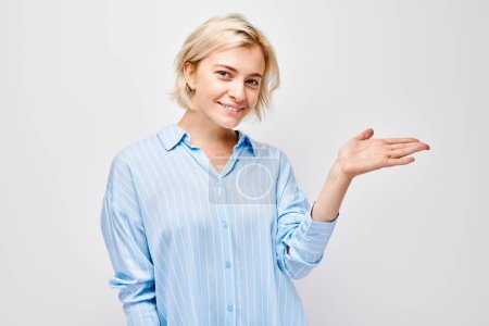Photo for Young blond woman in casual holding something in hand, demonstrating empty space for product or text isolated on white studio backgroun - Royalty Free Image