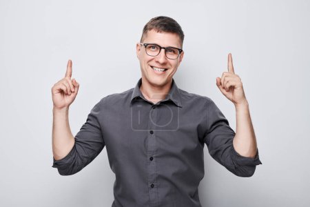Photo for Handsome man in glasses pointing up finger, demonstrating empty space for product or text isolated on white studio backgroun - Royalty Free Image