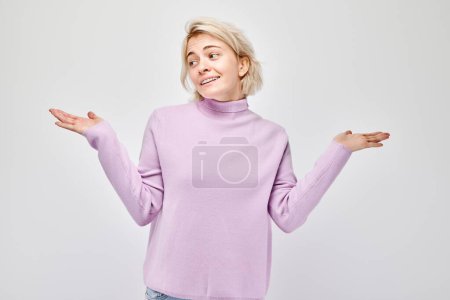 Photo for Young blond woman in casual holding something in hand, demonstrating empty space for product or text isolated on white studio backgroun - Royalty Free Image