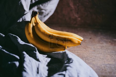 Foto de Primer plano de un ramo de plátanos sobre un fondo de tela oscura - Imagen libre de derechos