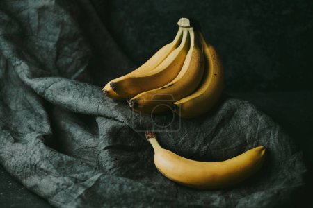 Photo for Close-up of a bunch of bananas on a dark fabric background - Royalty Free Image