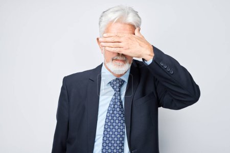 Photo for Portrait of elderly man covering eyes with hand isolated on white studio backgroun - Royalty Free Image