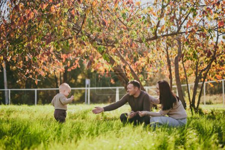 Foto de Retrato feliz familia mamá papá e hijo divertirse y disfrutar de pasar tiempo juntos en el parque de otoño en el día soleado. Amor y lealtad, padres jóvenes - Imagen libre de derechos