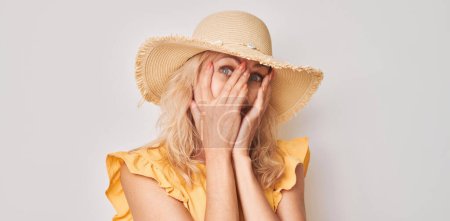 Téléchargez les photos : Portrait de femme couvrant les yeux avec la main, regardant à travers les doigts isolés sur fond de studio blanc - en image libre de droit