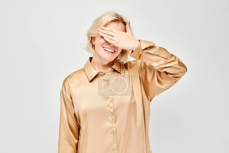 Photo for Portrait of young blonde woman covering eyes with hand isolated on white studio backgroun - Royalty Free Image