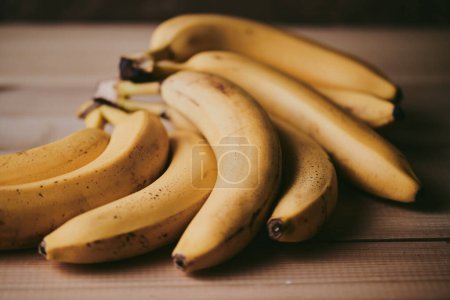 Téléchargez les photos : Gros plan d'un bouquet de bananes sur un fond de table de cuisine en bois - en image libre de droit