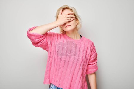 Foto de Retrato de mujer rubia joven cubriendo los ojos con la mano aislada en el fondo del estudio blanco - Imagen libre de derechos