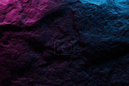 Foto de Textura de piedra negra en iluminación de neón azul rosado, fondo abstracto oscuro. Piedra mineral natural cerca de los detalles, fondo vacío con espacio de copia para el diseño - Imagen libre de derechos