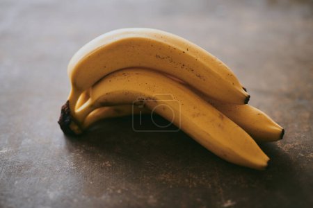 Téléchargez les photos : Gros plan d'un bouquet de bananes sur un fond brun texturé - en image libre de droit